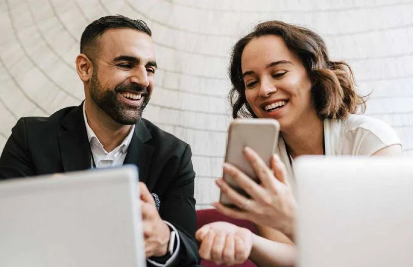 Image featuring a man and a woman laughing while looking at a smartphone, representing Datafield Technology Services. The image highlights Custom RFP Solutions, emphasizing alignment with the page's context.