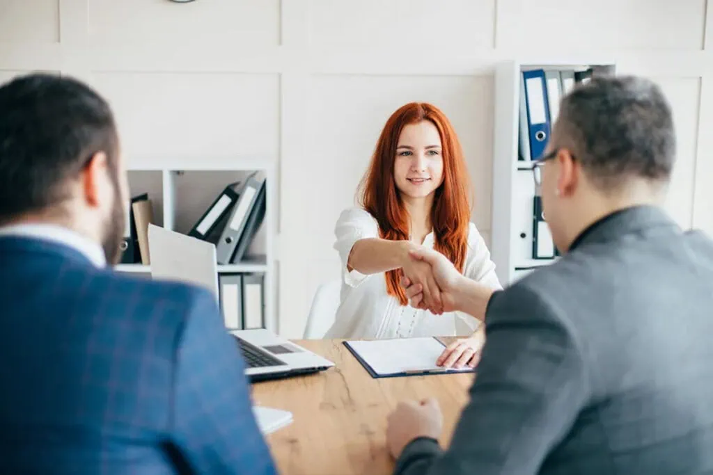 A woman shaking hands with two men at a meeting, featuring Data Field Technology Services and highlighting their expertise in innovative tech solutions.