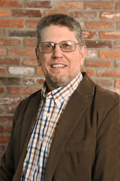 Portrait of a man with a confident expression, standing in front of the Datafield Technology Services logo. The man, identified as Matt Winger, appears to be a prominent figure associated with the company.