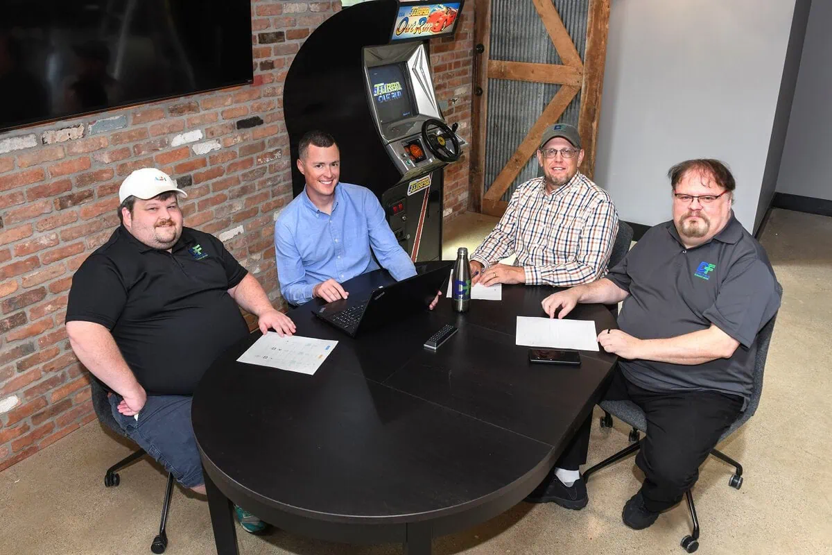 Three men sitting at a table with laptops, featuring Data Field Technology Services and highlighting their expertise in innovative tech solutions.